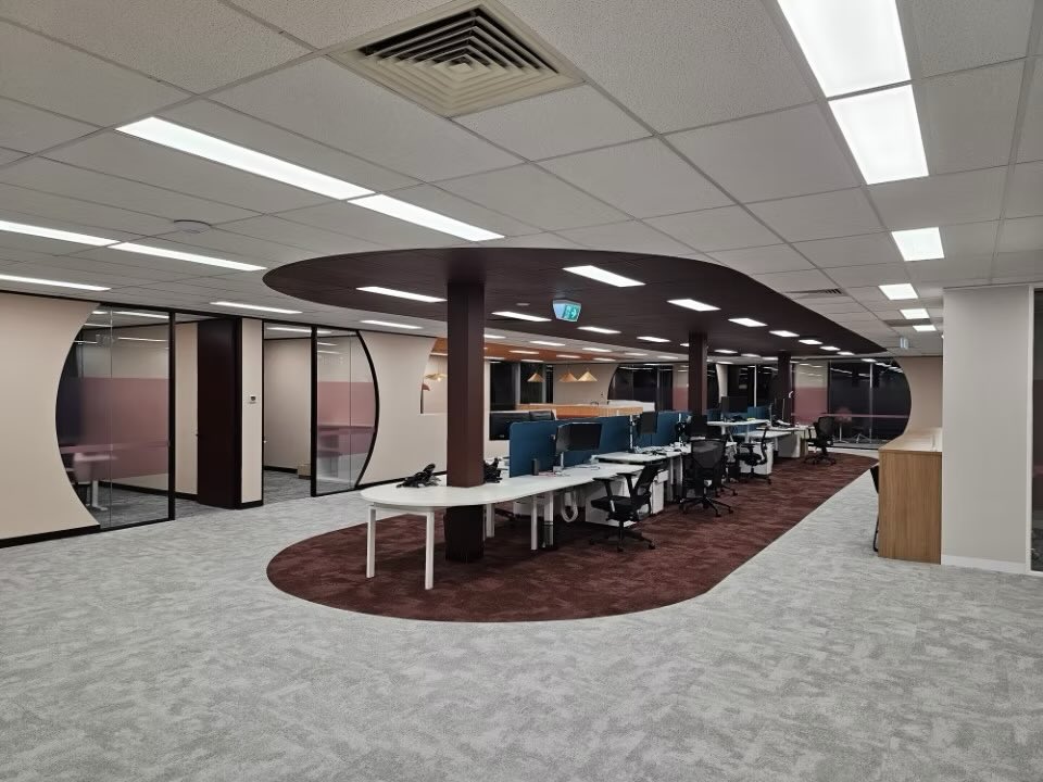 Open-plan office fit out in Port Melbourne with collaborative workstations, curved ceiling feature, and modern glass-partitioned meeting rooms